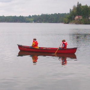 two boys paddling red canoe