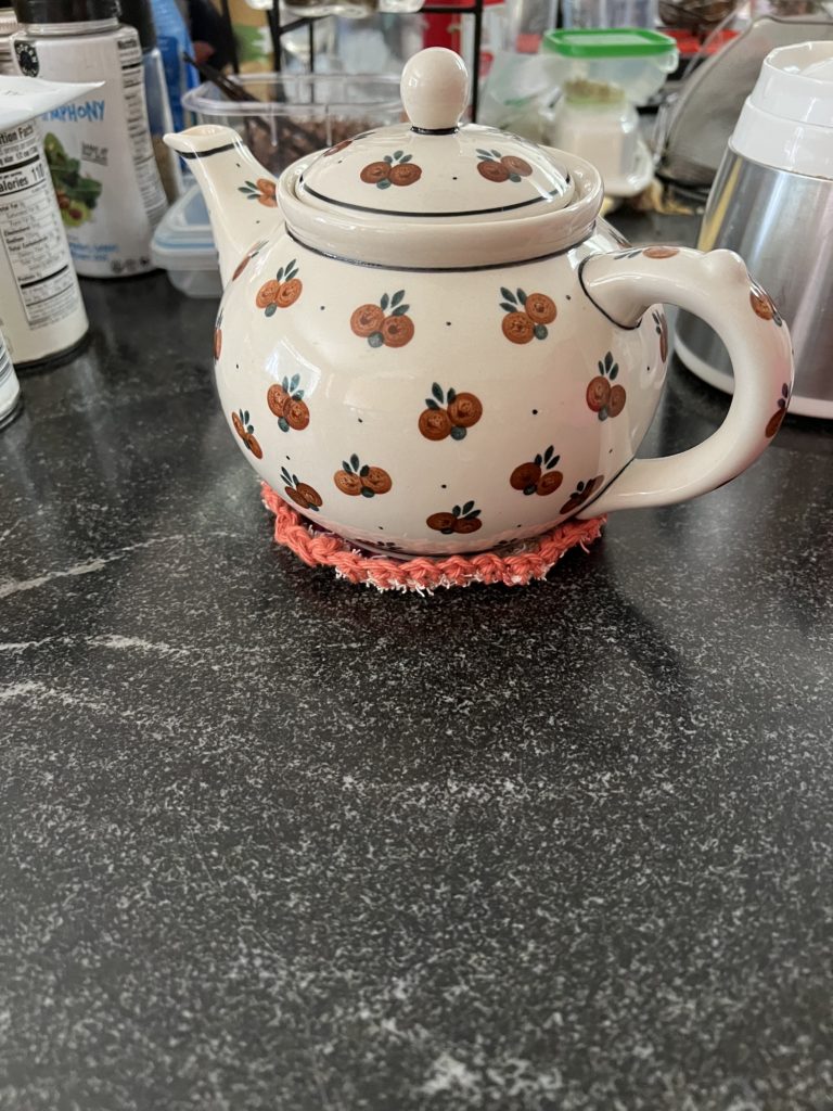 Polish-made teapot holds 8 cups on kitchen counter, on top of pink trivet.