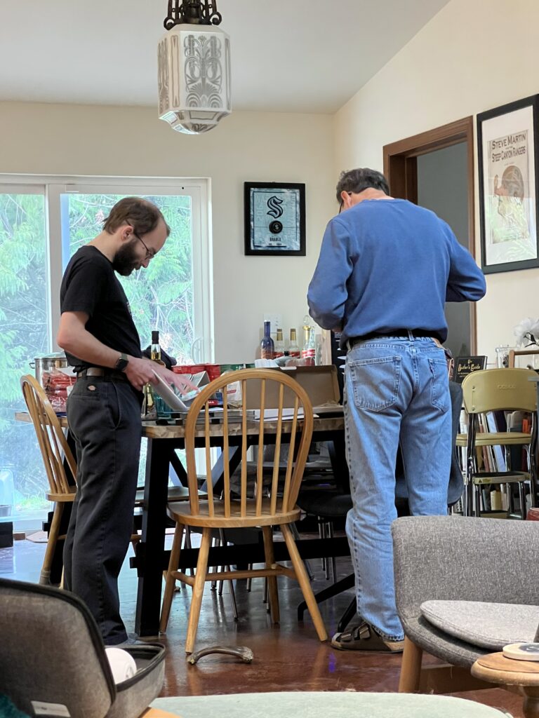 a young man and his father looking at items on a table